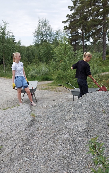 Frida Olsen Stakset (17) og Lotta Tangstad (14) henter grus i fra haugen og triller det bort til stien - Klikk for stort bilde